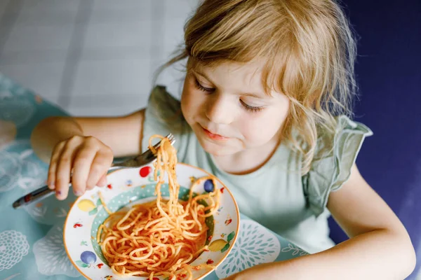 Menina adorável criança comer espaguete macarrão com bolonhesa de tomate com carne picada. Criança pré-escolar feliz comendo refeição saudável cozida fresca com macarrão e legumes em casa, dentro de casa. — Fotografia de Stock