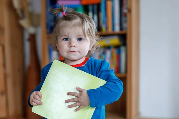 Küçük kız elinde kitap tutuyor. Mutlu çocuk kelimeleri öğreniyor ve resimlere bakıyor. Çocuklar ve çocuklar için geliştirme adımları. — Stok fotoğraf