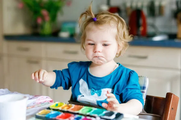Nettes glückliches kleines Mädchen, das mit Aquarell auf Papier malt. Baby lernt verschiedene Fertigkeiten, kreative Freizeit und Aktivität für kleine Kinder. — Stockfoto