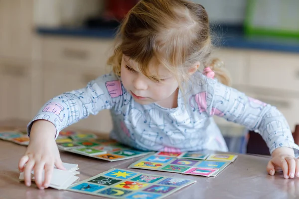 Emocionado sonriente linda niña jugando juego de cartas imagen. Feliz niño sano entrenando la memoria, pensando. Creativo en interiores de ocio y educación de los niños. Actividad familiar en casa. — Foto de Stock