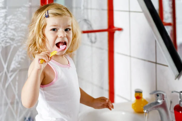 Mignonne adorable tout-petit fille tenant brosse à dents et brosser les premières dents dans la salle de bain après le sommeil. Magnifique bébé enfant apprenant à nettoyer la dent de lait. Matin routine d'hygiène saine pour les enfants — Photo