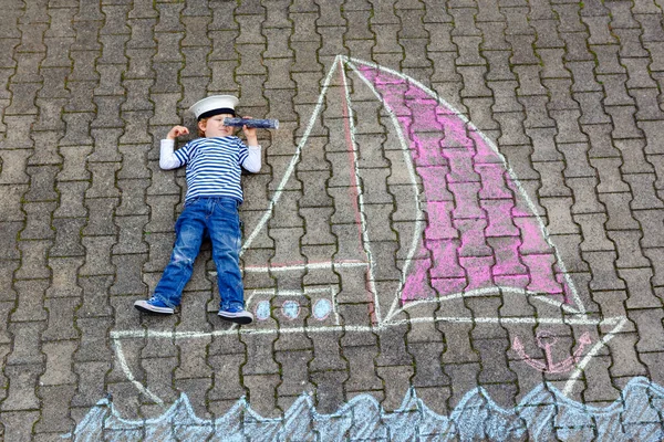 小男孩作为海盗在船上或 sailingboat 画与彩色粉笔在沥青。夏季户外儿童的创造性休闲。儿童与上尉帽子和望远镜. — 图库照片