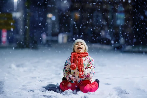 可爱的小女孩冬天在户外散步 傍晚下大雪时 可爱的幼儿 孩子在雪地里玩得开心 穿着温暖的婴儿色彩艳丽的衣服 头戴有泡泡的帽子 — 图库照片