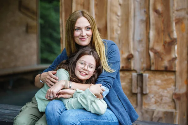 Portrait of little school girl with glasses and mother hugging together. Cute daughter and happy woman. family, childhood, happiness and people.