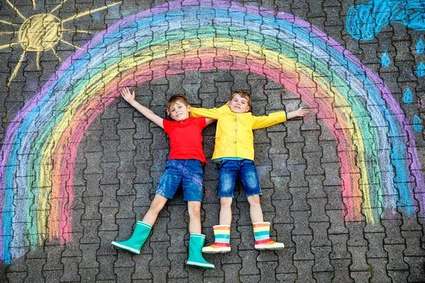 两个快乐的学童正在玩彩虹图画 用彩色粉笔画沥青 兄弟姐妹 双胞胎和最好的朋友一起在地上画画 签署对抗Corona病毒 — 图库照片