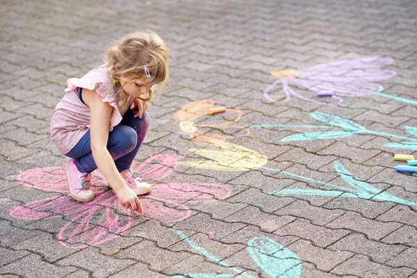 裏庭の地面にカラフルなチョークの花で小さな就学前の女の子の絵 積極的な幸せな幼児の子供はアスファルトの上に絵を描くと作成します 夏の創造的な屋外の子供の活動 — ストック写真