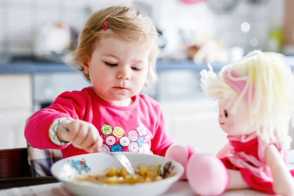 かわいい赤ちゃん女の子フォーク野菜やパスタを食べるします 餌と開発コンセプト かわいい幼児 スプーンでハイチェアに座っていると ひとりでに食べ方を学ぶ娘 — ストック写真