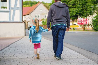Mutlu çocuk anaokulu kızı gülümser ve okulun ilk güneşli gününde babasının elini tutar. Baba ve kızı anaokuluna gidiyor, birlikte eğleniyorlar. Gözlüklü çocuk