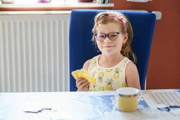 Little preschool girl with glasses playing card game. Happy healthy child training memory, thinking. Creative indoors leisure and education for family and kids