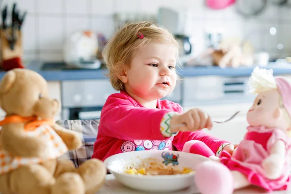 かわいい赤ちゃん女の子フォーク野菜やパスタを食べるします 餌と開発コンセプト かわいい幼児 スプーンでハイチェアに座っていると ひとりでに食べ方を学ぶ娘 — ストック写真