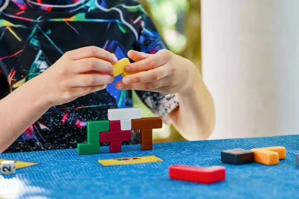 School boy playing board game with colorful bricks. Happy child build tower of wooden blocks, developing fine motor skills, home joint games. Leisure activities for children at home