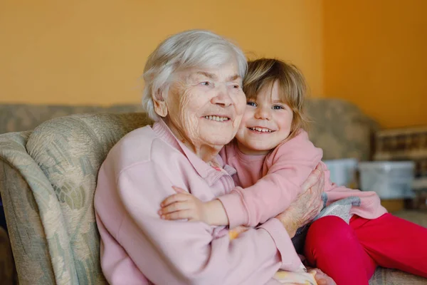 漂亮的幼儿女孩和曾祖母在家里拥抱在一起 可爱的孩子和年长的女人在一起玩乐 在室内快乐的家庭 — 图库照片