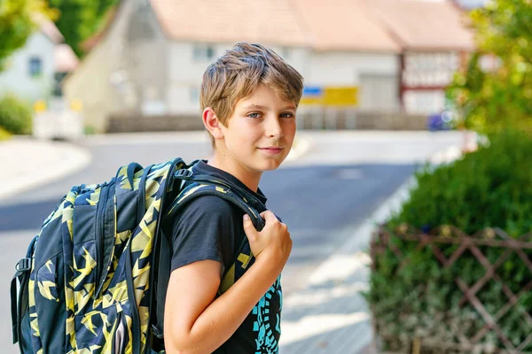 サッチェルを持った幸せな十代の少年が歩いている 中学や高校に行く途中の小学生 学校の庭の外で興奮した子供 学校に戻る — ストック写真
