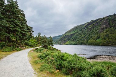 Idyllic view in Glendalough Valley, County Wicklow, Ireland. Mountains, lake and tourists walking paths. clipart