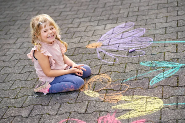 裏庭の地面にカラフルなチョークの花で小さな就学前の女の子の絵 積極的な幸せな幼児の子供はアスファルトの上に絵を描くと作成します 夏の創造的な屋外の子供の活動 — ストック写真