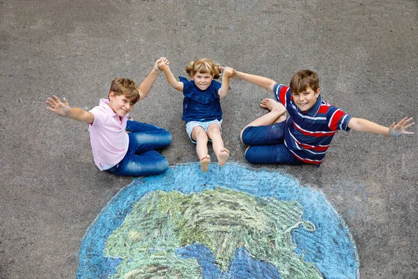 学龄前小女孩和两个小学生 带着绘有彩色粉笔的地球仪画在地上 快乐地球日的概念 为拯救世界 环境和生态而创造儿童 — 图库照片