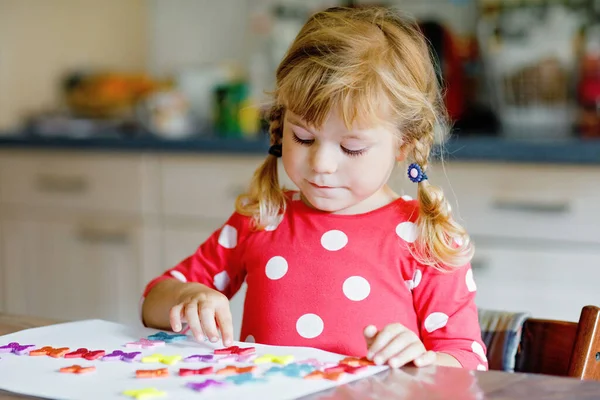 蹒跚学步的小女孩玩着不同颜色的贴纸和画着花 儿童在大流行性日冕病毒检疫期间的活动概念 在家里和父母一起学习颜色的孩子 — 图库照片