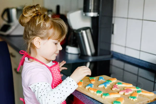 かわいい幼児の女の子と焼きたての自家製イースターや自宅で春のクッキー屋内 家庭用キッチンでウサギとニンジンクッキーとエプロンと愛らしいブロンドの子供 お子様クッキー — ストック写真