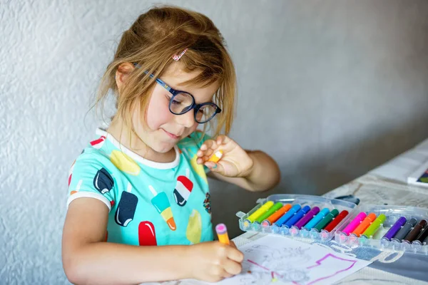 快乐的学龄前女孩带着眼镜 学习用彩色铅笔和毛笔画画 夏天阳光灿烂的日子 小孩子在家里画画 用彩笔 为儿童开展的创造性活动 — 图库照片