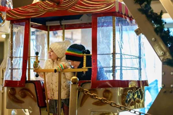 上幼儿园的小女孩骑着摩天轮旋转木马在户外的圣诞游乐场或市场上玩耍 在德国传统的家庭圣诞市场上玩得开心的幼儿 — 图库照片