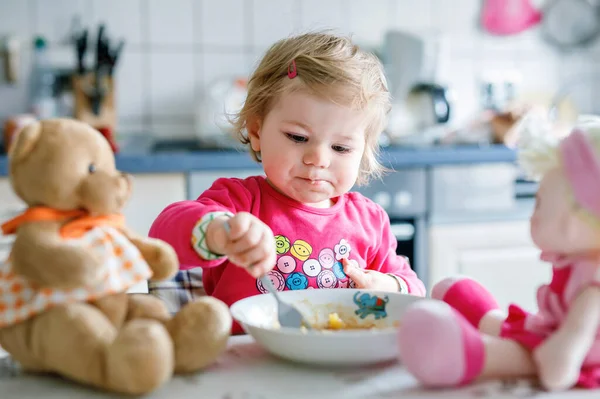 かわいい赤ちゃん女の子フォーク野菜やパスタを食べるします 餌と開発コンセプト かわいい幼児 スプーンでハイチェアに座っていると ひとりでに食べ方を学ぶ娘 — ストック写真