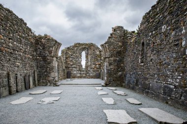Taş yuvarlak kule ve bir manastır yerleşim bazı kalıntıları aslında Glendalough vadisinde 6 yüzyılda inşa, County Wicklow, İrlanda güneşli bir günde.