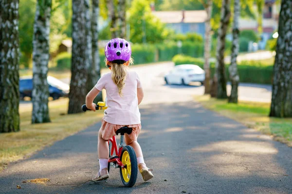 夏の日にバランスバイクで走るヘルメット付きの小さな就学前の女の子 幸せな子供の運転 自転車でのサイクリング 屋外活動 子供時代 子供の夏の活動 — ストック写真