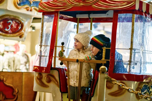 在户外的圣诞游乐场或市场上 学龄前小女孩和学童骑着摩天轮旋转木马 两个快乐的孩子在德国传统的家庭圣诞市场上玩得很开心 — 图库照片