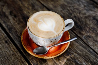 Açık bir kafede ya da restoranda tahta bir masanın üzerinde bir fincan düz beyaz kahve. Kırsal biçim