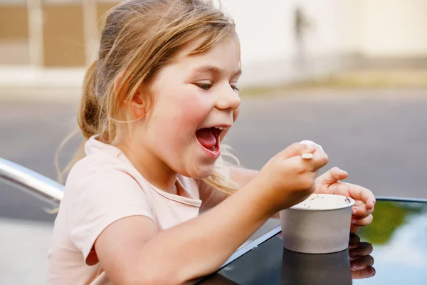 在阳光灿烂的夏日 一个可爱的学龄前小女孩在杯子里吃冰淇淋圣代 快乐的幼儿吃冰淇淋甜点 炎热温暖的夏天吃甜食 — 图库照片