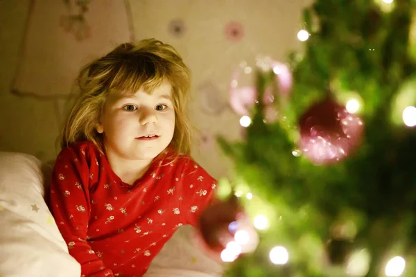 小可爱的幼儿小女孩躺在圣诞树下 在家里梦到圣诞老人 在屋里 传统的基督教节日 快乐的孩子在圣诞节等待礼物 舒适柔和的光线 — 图库照片