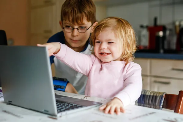 可爱的小女孩和小学生男孩 看着笔记本电脑 两个孩子 用电脑或笔记本 给孩子们用电脑上的电子学习 兄弟姐妹和家庭 — 图库照片