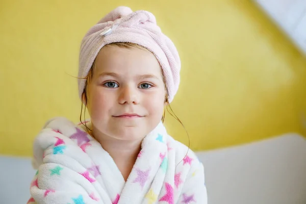 洗完澡后的学龄前儿童 可爱的小女孩 一头湿湿的卷发 身穿浴衣 头戴毛巾 坐在床上 婴儿和儿童用卫生间纺织品 — 图库照片