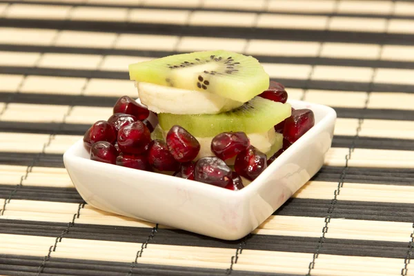 Trozos de plátano de frutas, kiwi, granada en bandeja pequeña —  Fotos de Stock