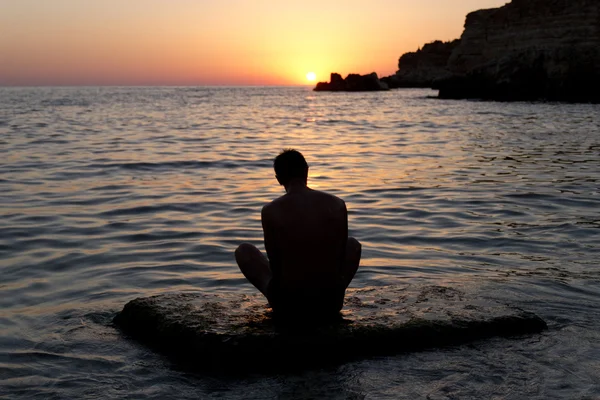 Мужчина медитирует на закате — стоковое фото