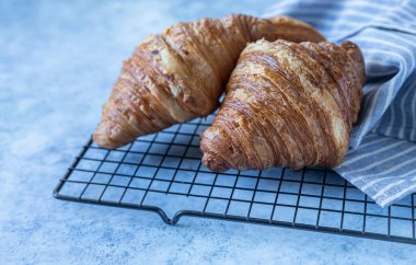 Lezzetli çıtır kruvasanlar, mavi beton arka plan. Kahvaltı için fırın.