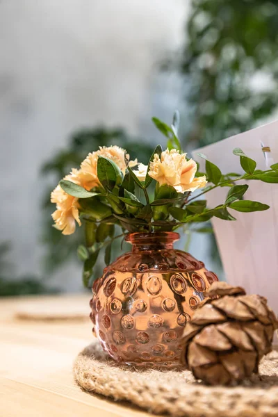 Café o cafetería interior con flores y hojas verdes en jarrón decorativo, fondo borroso. Colores neutros, estilo simple. — Foto de Stock