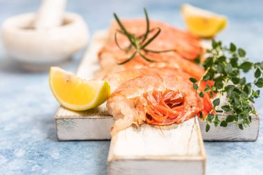 Beyaz ahşap tahta üzerinde çiğ Arjantin karidesleri kireç, bitki ve biberli kesme tahtası. Deniz ürünleri. Kapat..