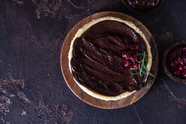 Çikolata soslu kremalı cheesecake ve koyu beton arka planda biberiyeyle süslenmiş kiraz..
