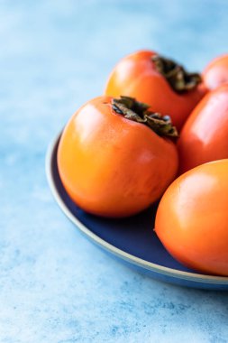 Mavi beton arka planda taze organik olgun hurmalar..