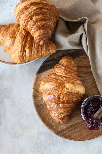 Fresh crispy croissants with jam, concrete background. Homemade bakery for tasty breakfast. Top view. — Stock Photo, Image