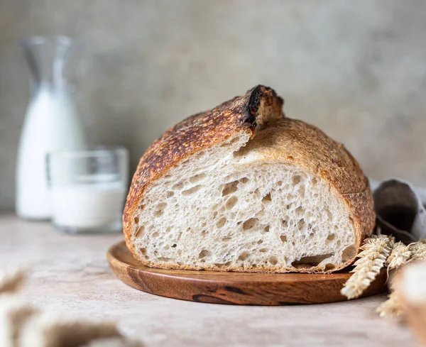 Кусок свежеиспеченного хлеба из запеченного теста на доске с молоком. Хлеб из ручного теста. — стоковое фото