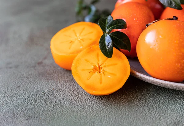 Whole Cut Persimmon Fruit Water Drops Green Leaves Green Concrete — Stock Photo, Image