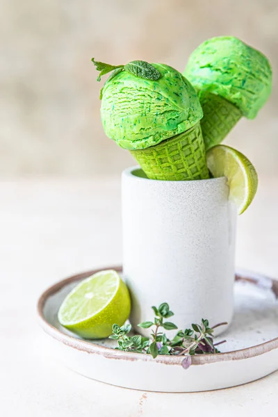 Homemade green ice cream with lime and mint in green waffle cone. Summer dessert. Selective focus.