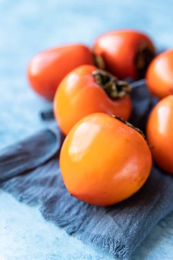 Mavi beton arka planda taze organik olgun hurmalar..