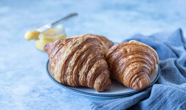 Fransk croissant. Nybakade croissanter med honung på blå betong bakgrund. — Stockfoto
