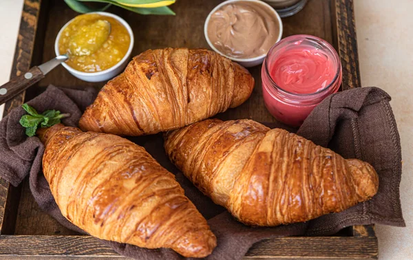 Gammal trälåda med krispiga croissanter, sylt, chokladkräm och kaffe. Frukostdags. — Stockfoto