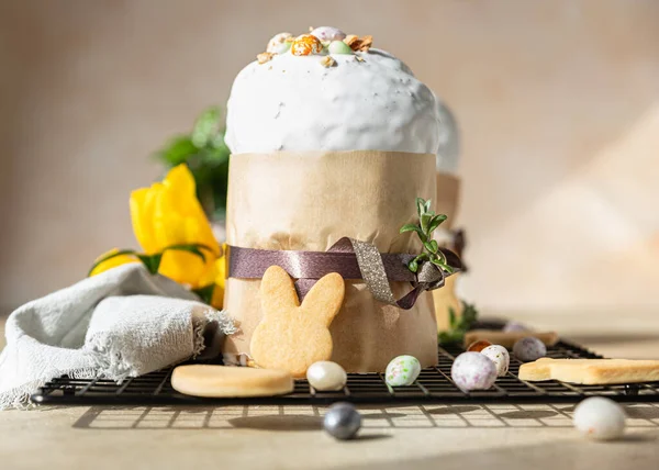 Kulich. Traditional Orthodox Easter sweet bread decorated with meringue icing and candy shaped eggs on black metal grille. — Stock Photo, Image