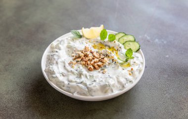 Geleneksel Bulgar soğuk yaz çorbası taratörü yeşil arka planda malzemelerle. Bulgar çorbası rendelenmiş salatalık, yoğurt ve ceviz.