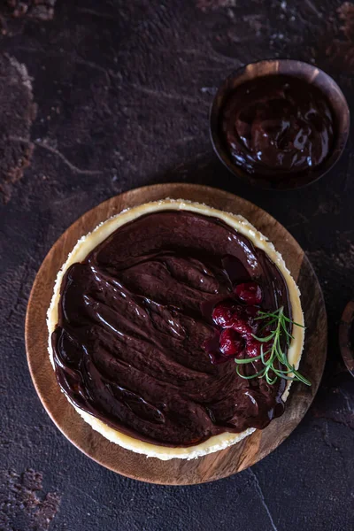 Çikolata soslu kremalı cheesecake ve koyu beton arka planda biberiyeyle süslenmiş kiraz..